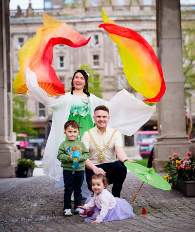 The Lord Mayor of Belfast, Councillor Ryan Murphy, joins Dessie and Farrah Doyle, along with Arts Ekta performer Weihong outside City Hall in Belfast 