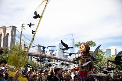 Little Amal standing among a crowd near Brooklyn Bridge New York