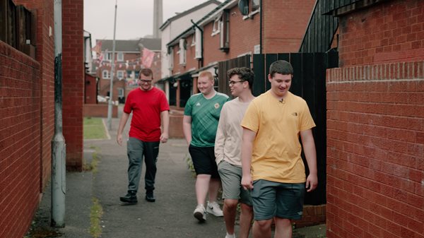 A group of four boys walking down an alleyway.