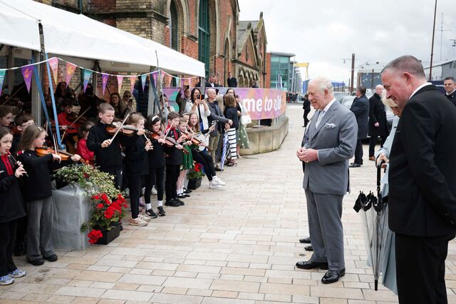 Irish dancers welcome King Charles as he plays the bodhrán.