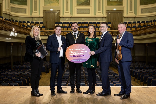 Deputy Lord Mayor of Belfast and reps from partner organisations holding a photo prop on the stage at the Ulster Hall