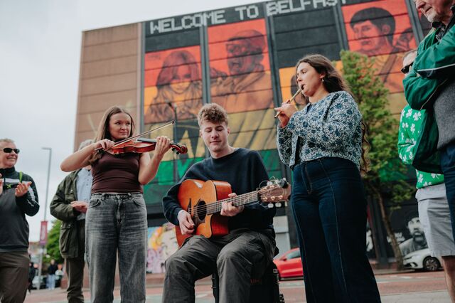 Traditional musicians play in front of the UNESCO City of Music mural
