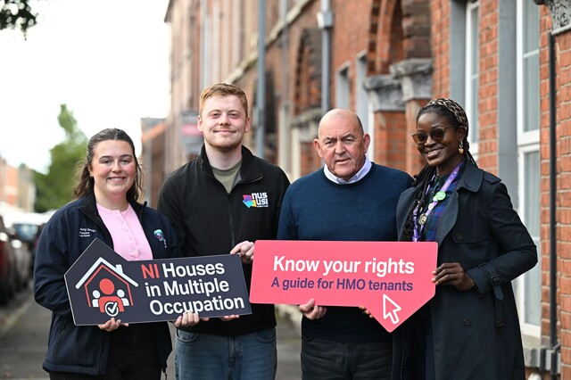 Student representative and the deputy Chair of Belfast City Council's licensing committee holding photo props with terraced housing in the background