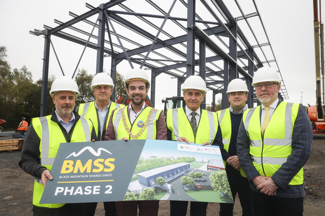 Belfast Lord Mayor with funders and reps from Black Mountain Shared Space on site in high vis vests and hard hats with artist impression of new building