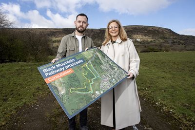 Micheal Donnelly from Upper Springfield Development Trust and Councillor Christina Black on Black Mountain with photo prop and text Black Mountain consultation