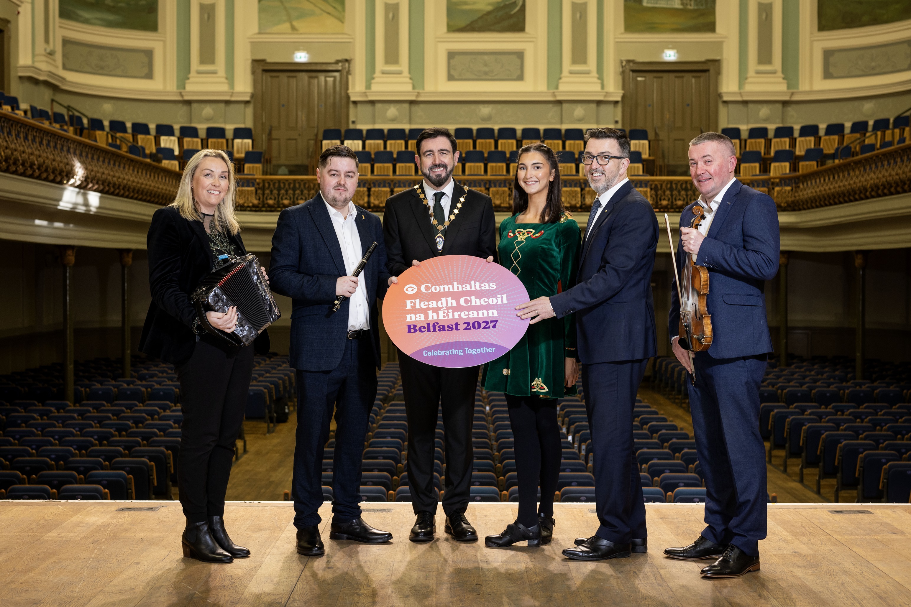 Deputy Lord Mayor of Belfast and reps from partner organisations holding a photo prop on the stage at the Ulster Hall