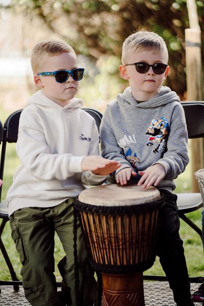Two young boys wearing sunglasses playing the drums