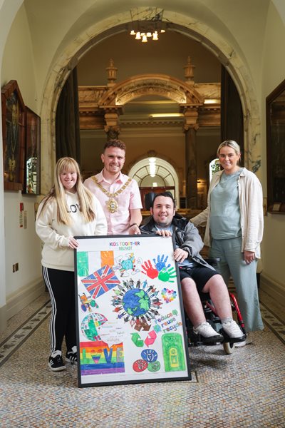 Lord Mayor Ryan Murphy pictured at City Hall with members of Kids Together Belfast and a picture of their art work.