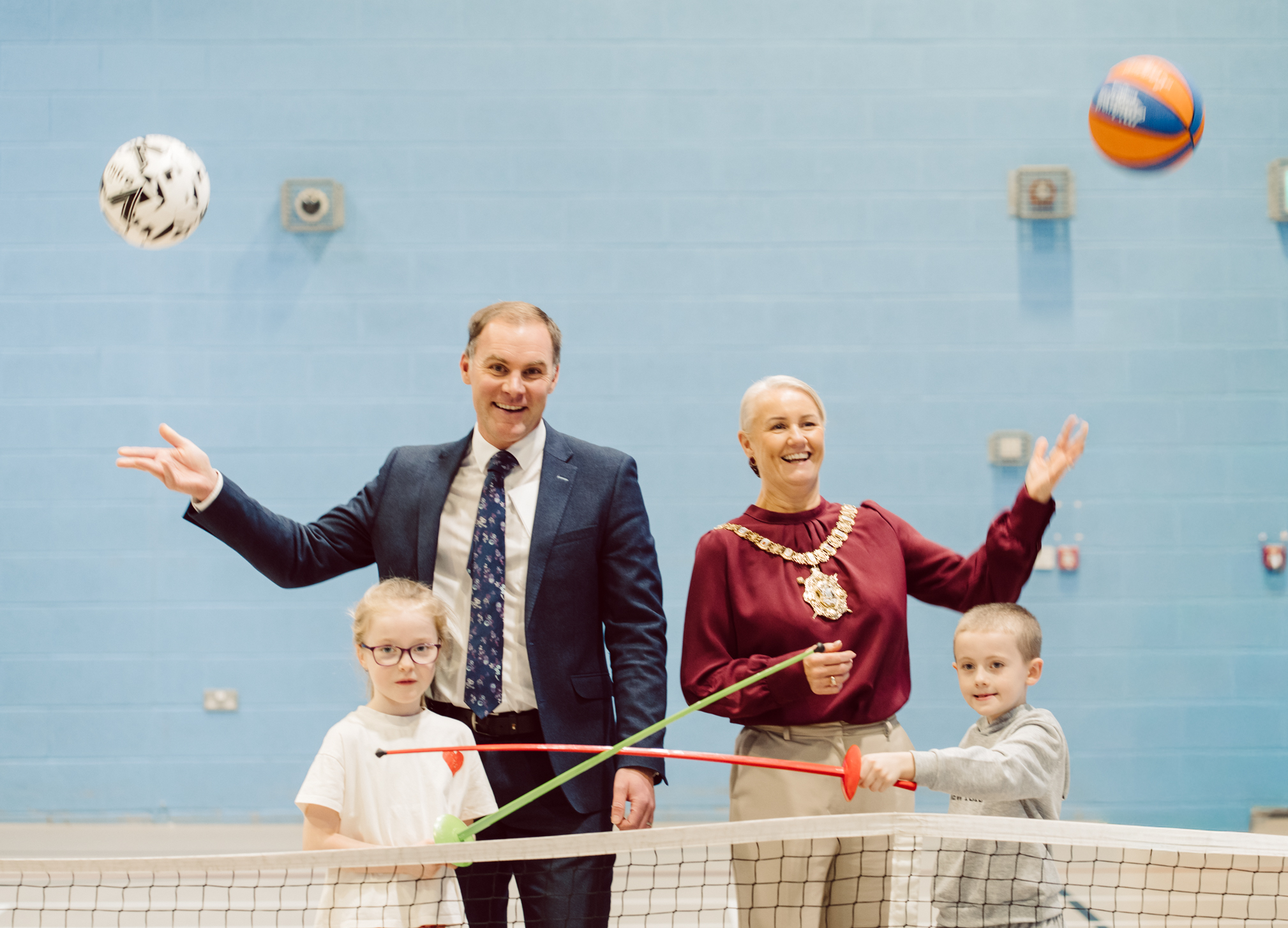 Gareth Kirk, Senior Regional Director with GLL, and Lord Mayor of Belfast, Councillor Tracy Kelly pictured with two young sportspeople and sporting equipment