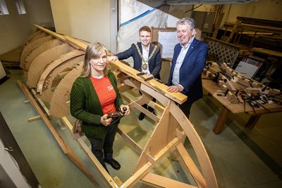 Boatbuilder Niamh Scullion, Lord Mayor of Belfast, Councillor Ryan Murphy, and Dr Paul Mullan, from The Heritage Lottery Fund, with the St Ayles skiff, which is under construction.