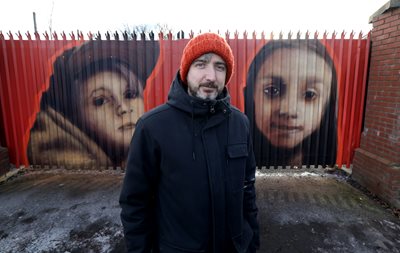 Artist Emic in front of the artwork on the black gates 
