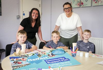 Three boys and two women pictured with arts and crafts materials and gathered around a table together.