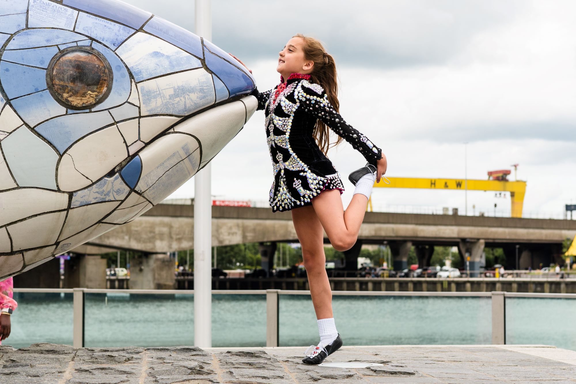 Fleadh competitor warms up by the Big Fish with H&W cranes in the backgroudn