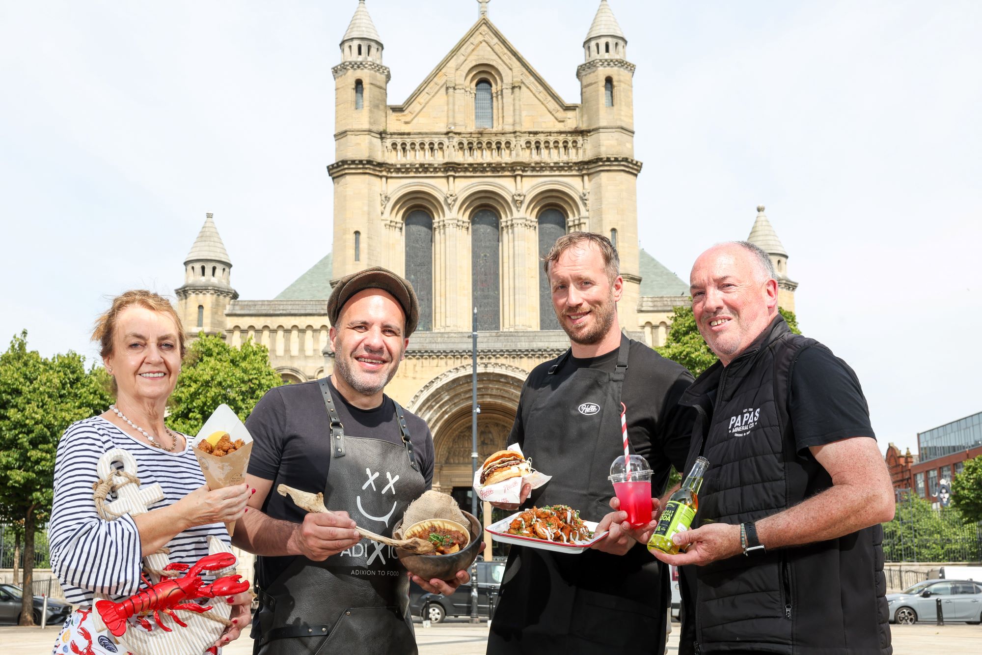 Food traders holding plates of food outside Belfast Catherdral.