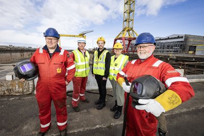 Harland and Wolff employees join the Lord Mayor of Belfast and representatives from Harland and Wolff and Unite the Union under the famous shipyard cranes.