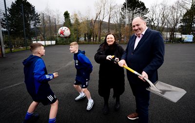 Two boys from Shankill Juniors heading ball with Councillor Nicola Verner and Conrad Kirkwood, President of the Irish FA, holding a shovel