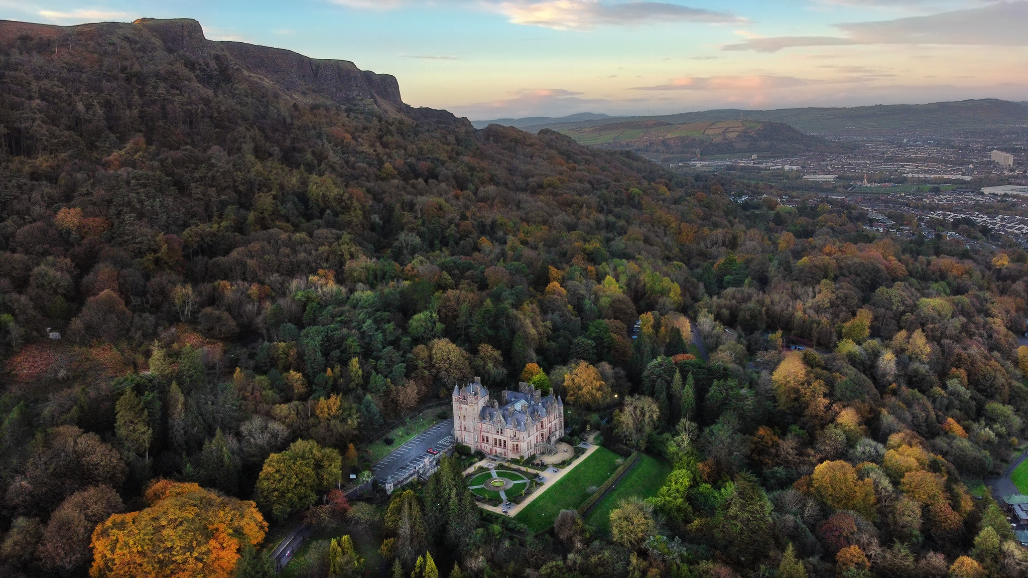 Belfast Castle surrounded by trees and a blue sky.