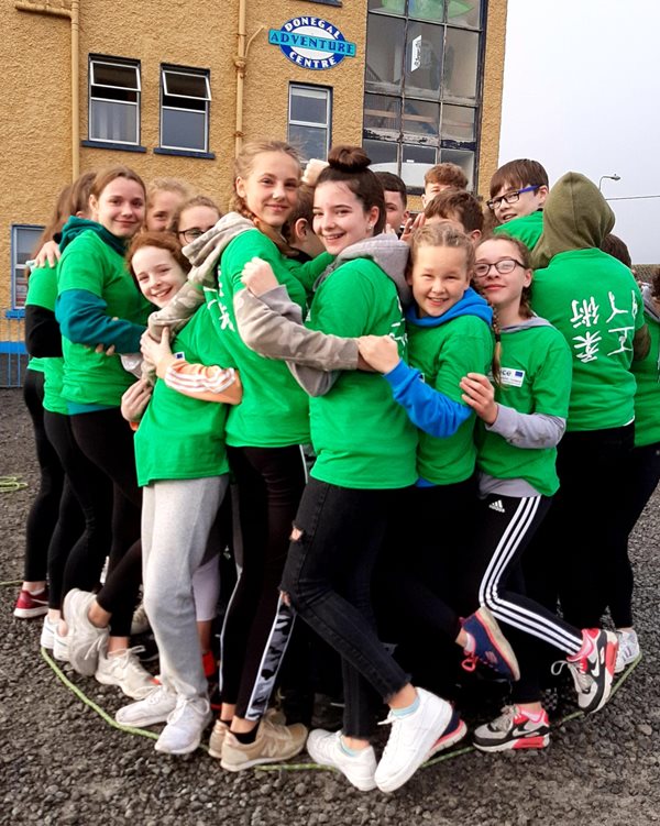 A group of children wearing green jumpers outside a building.