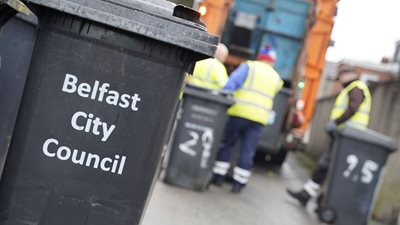Belfast City Council black bin with a bin lorry in background