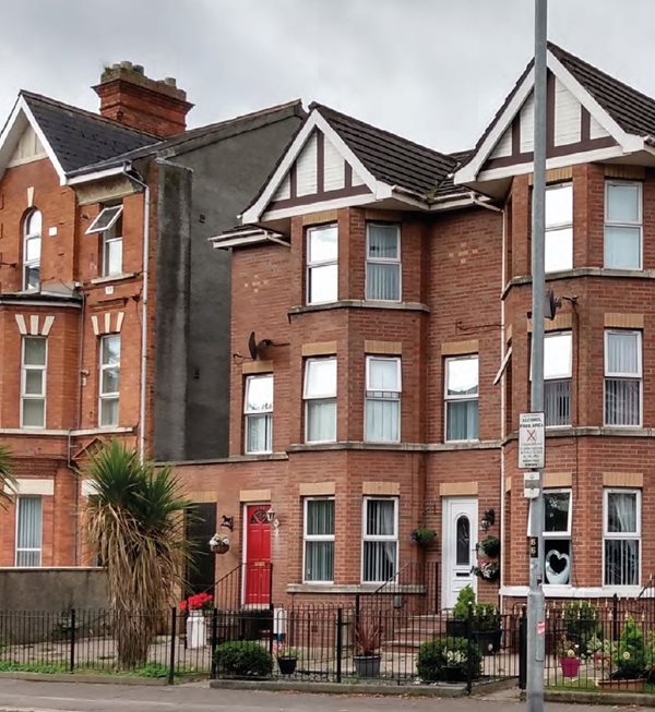 Row of red brick three storey townhouses showing how new housing can be built to remain in keeping with the architectural style and character of existing, older housing in the vicinity.