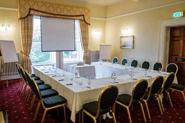 Ashley Room with a large table and chairs and screen in a u-shape style setup.