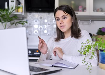 A woman speaks while seated in front of a laptop computer