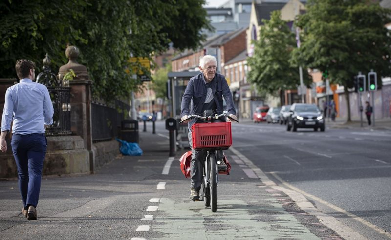 Man passing a pedestrian, as he cycles along Ormeau Road in Belfast.