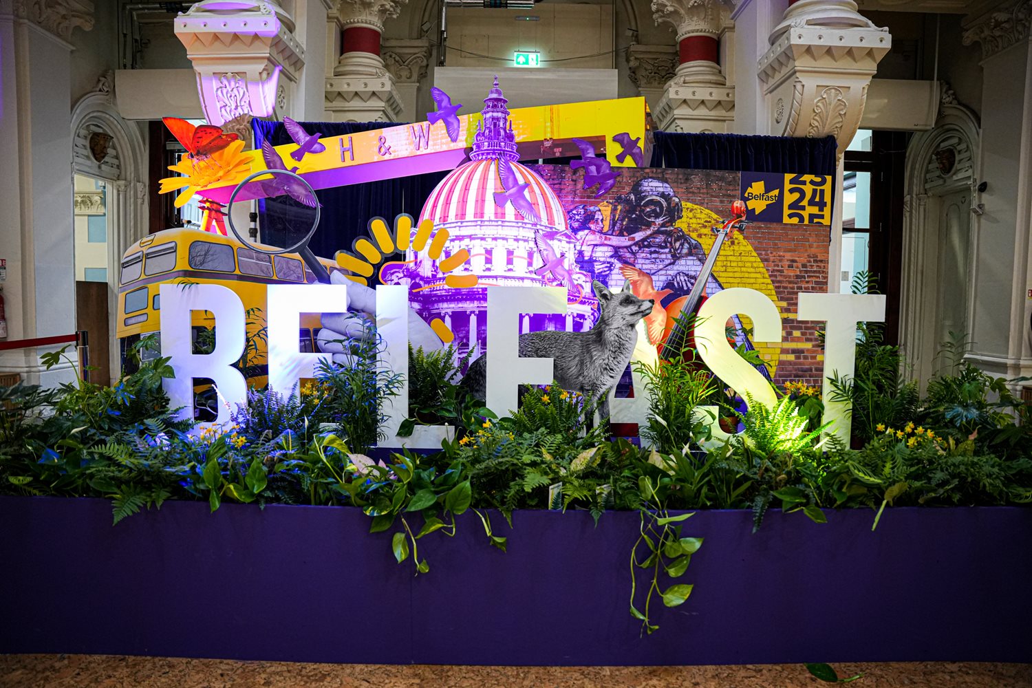 A colourful and engaging indoor display showing the word 'Belfast' surround by green leaves, flowers and creative imagery.