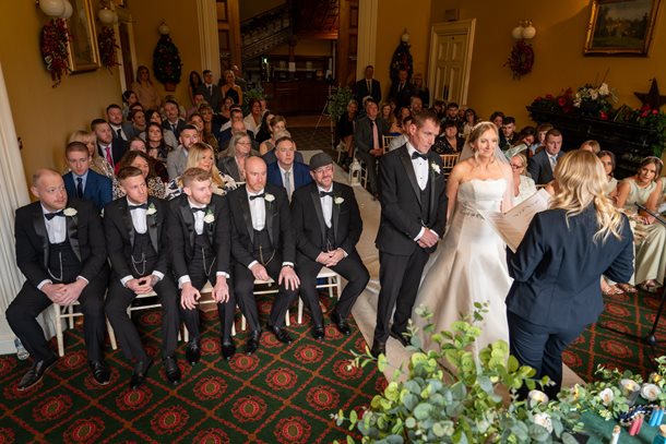 A wedding ceremony in the Donegall Room with Bride and Groom at the top of the aisle while guests watch on in a theatre-style set up.