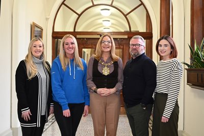 Belfast Lord Mayor Cllr Christina Black stands in corridor at City Hall with representatives from Active Communities Network, a charity organisation.