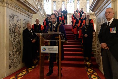 The High Sheriff of Belfast Councillor John Hussey dressed in ceremonial robes reads the Accession Proclamation on the main staircase at City Hall, surrounded by Members of Belfast City Council