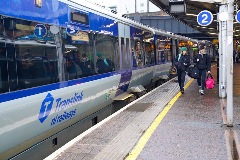 Man and woman carrying luggage as they leave a Translink train at Lanyon Place station in Belfast.