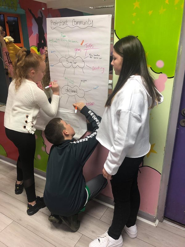 Three children drawing on a flip chart.