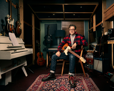 Tom Gray holding a guitar in a recording studio