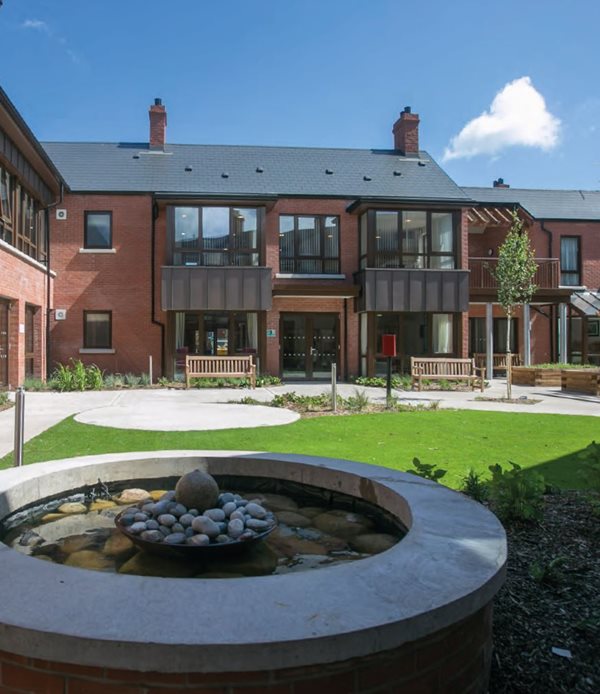 Residential units framing a communal garden that has a mix of hard and soft landscaping and seating for shared use by local residents.