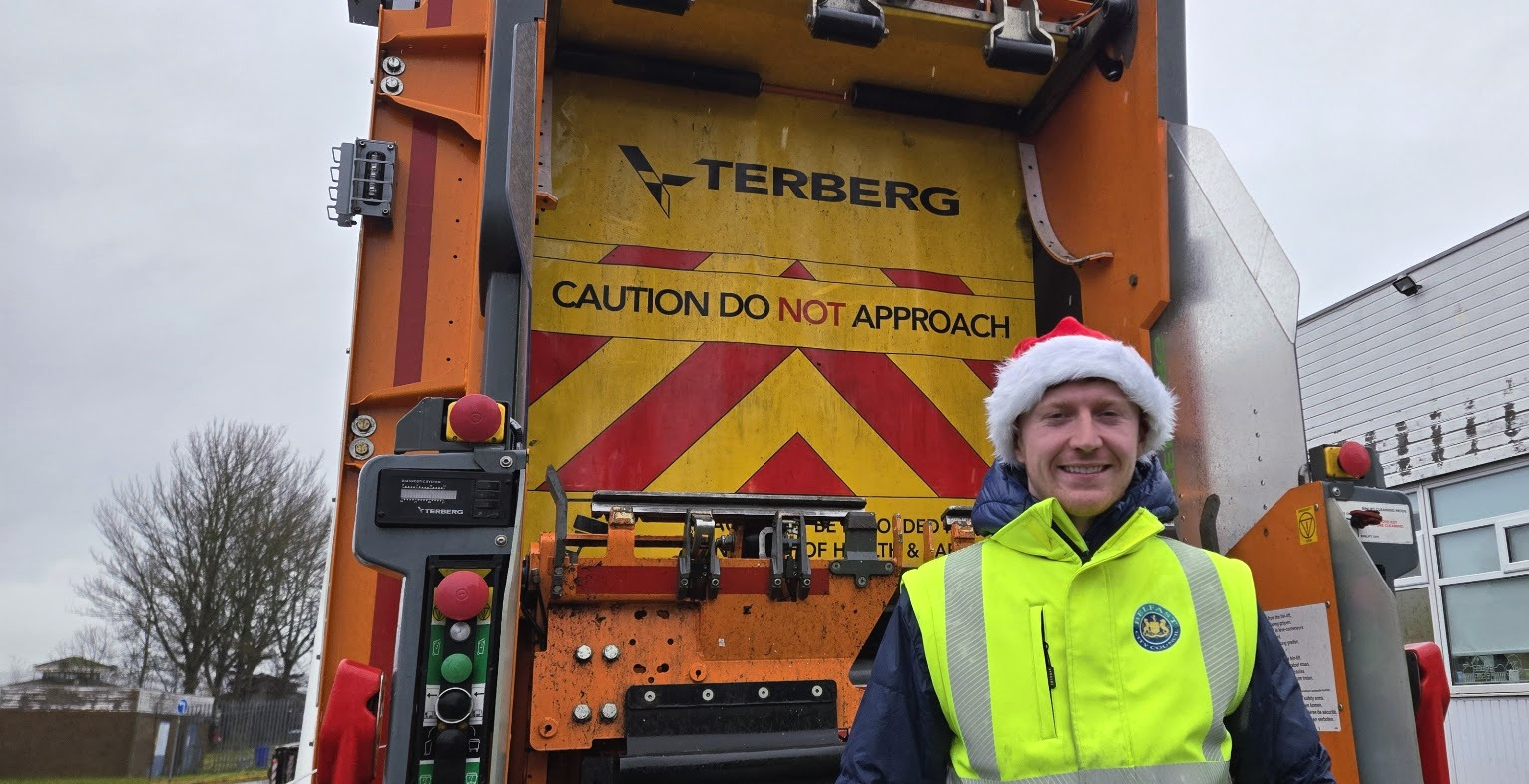 Bin lorry with a member of the bin crew standing wearing a Santa hat